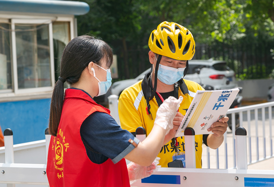 志愿者在社區(qū)門(mén)口接送快遞。石家莊市文明辦供圖