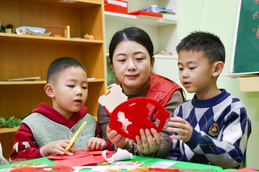 12月30日，在保定市競(jìng)秀區(qū)富昌鄉(xiāng)香溪茗苑社區(qū)，家長(zhǎng)和孩子們剪窗花。許昊攝