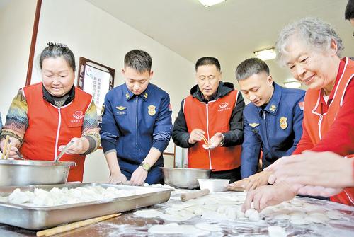 1月24日，在滄州市消防救援支隊(duì)浮陽北大道特勤站，“中國好人”崔建松（左三）帶領(lǐng)滄州市義務(wù)工作者協(xié)會志愿者和特勤站消防指戰(zhàn)員一起包餃子。 本報(bào)記者 王雅楠攝